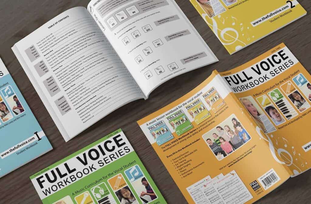 Full voice music workbooks on a wooden table